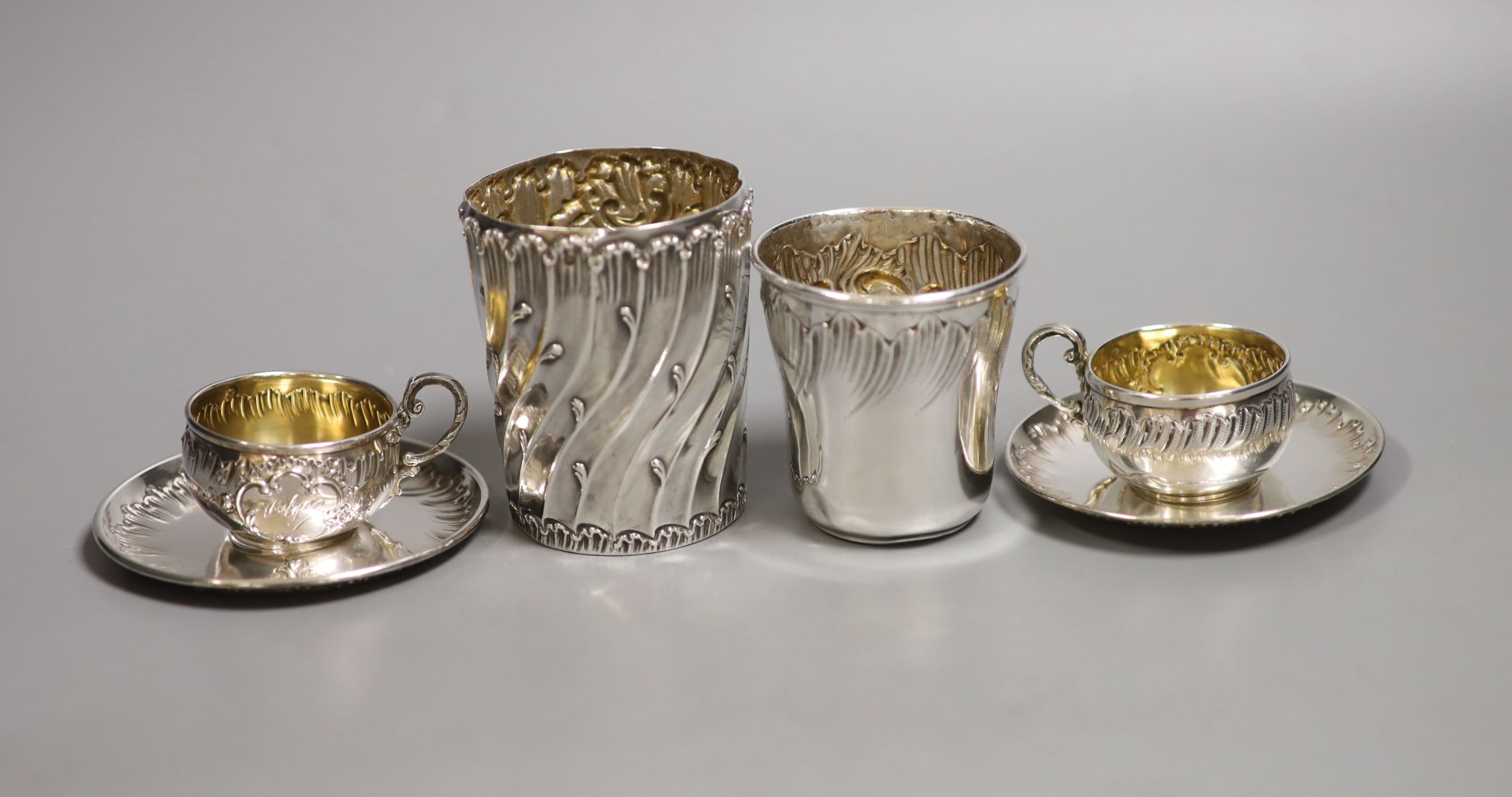 A pair of French white metal cups and saucers and two similar tumblers